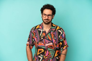 Genç sakallı adam gururlu, kendinden emin, havalı, küstah ve küstah görünüyor, gülümsüyor, başarılı hissediyor.