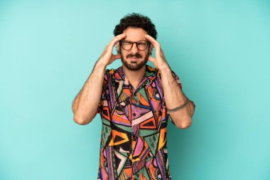Genç sakallı adam stresli ve hayal kırıklığına uğramış görünüyor, baskı altında çalışıyor ve başı ağrıyor.