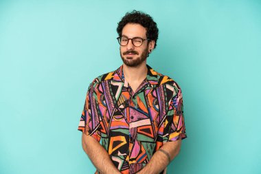 Genç sakallı adam mutlu ve arkadaş canlısı görünüyor, gülümsüyor ve sana olumlu bir tavırla göz kırpıyor.