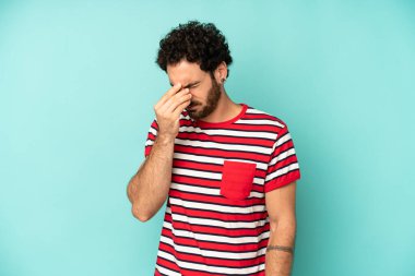 Genç sakallı adam stresli, mutsuz ve hayal kırıklığına uğramış, alınlı ve şiddetli baş ağrısı çeken.