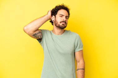 Genç sakallı adam şaşkın ve kafası karışmış hissediyor, başını kaşıyor ve yan tarafa bakıyor.