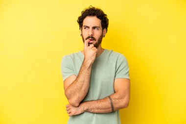 Şaşırmış, gergin, endişeli ya da korkmuş bakışları olan genç sakallı adam fotokopi uzayına bakıyor.