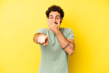 Genç sakallı adam sana gülüyor, kamerayı gösteriyor ve seninle dalga geçiyor ya da alay ediyor.