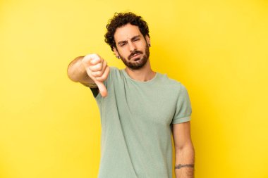 Genç sakallı adam sinirli, sinirli, hayal kırıklığına uğramış ya da canı sıkkın, ciddi bir bakışla başparmağını kaldırıyor.