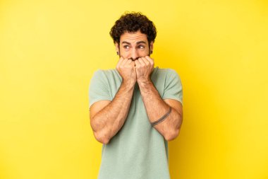 Genç sakallı adam endişeli, gergin, stresli ve korkmuş görünüyor tırnaklarını yiyor ve yanal fotokopi alanı arıyor.