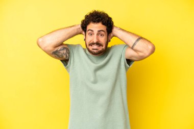 Genç sakallı adam kendini stresli, endişeli ya da korkmuş hissediyor. Elleri başının üstünde, hatayla panikliyor.