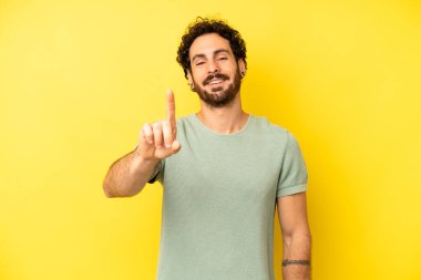 Genç sakallı adam gülümsüyor ve arkadaş canlısı görünüyor, bir numara ya da ilk eli önde, geriye doğru sayıyor.