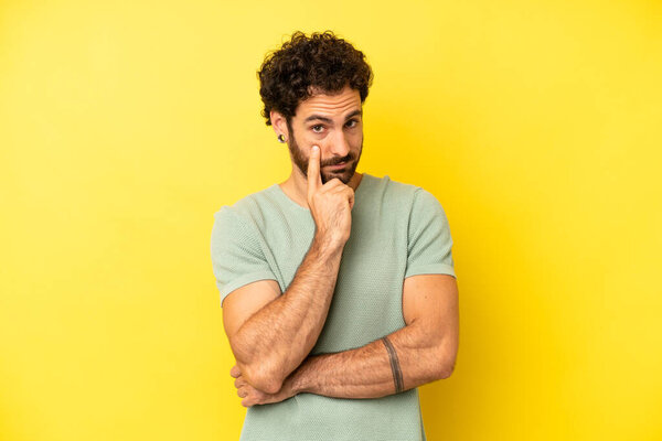 young bearded man keeping an eye on you, not trusting, watching and staying alert and vigilant