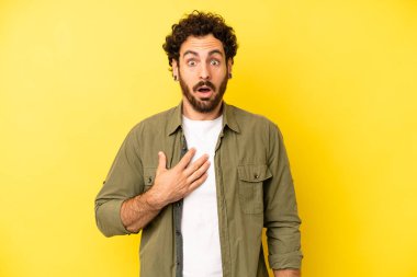 Genç sakallı adam şok olmuş, şaşırmış ve şaşırmış hissediyor, elleri göğsünde ve ağzı açık, kim olduğunu söylüyor, ben mi??