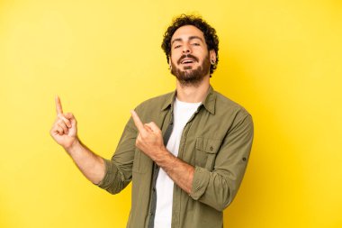 Genç sakallı adam mutlu bir şekilde gülümsüyor ve her iki elinde fotokopi alanında nesne gösteriyor.