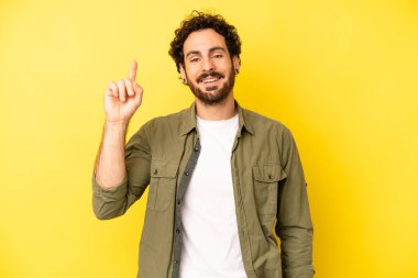 Genç sakallı adam mutlu bir şekilde gülümsüyor, tek eliyle uzayı işaret ediyor.