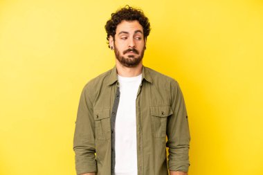 Genç sakallı adam merak ediyor, mutlu düşünceler ve fikirler düşünüyor, hayal kuruyor, kenarda yer arıyor.