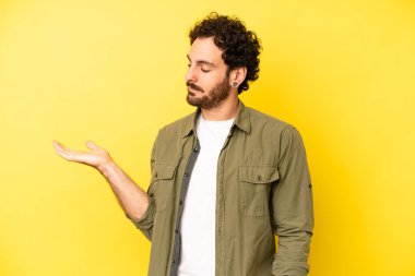 Genç sakallı adam kendini mutlu hissediyor ve gülümsüyor. Elinde tuttuğu bir nesneye ya da konsepte bakıyor.