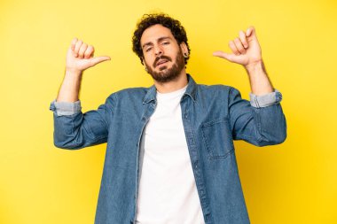 Genç sakallı adam gururlu, kibirli ve kendinden emin, tatmin olmuş ve başarılı görünüyor, kendini gösteriyor.