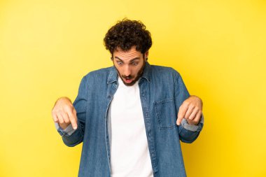 Genç sakallı adam şok olmuş, ağzı açık ve şaşırmış hissediyor. İnançsızlık ve şaşkınlık içinde bakıyor ve işaret ediyor.