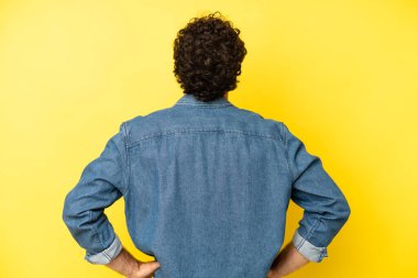 Genç sakallı adam kafası karışık ya da dolgun hissediyor ya da şüphe ve sorular, merak ediyor, elleri kalçasında, dikiz aynasından.