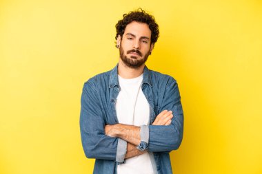 Genç sakallı adam hayal kırıklığına uğramış ve hayal kırıklığına uğramış hissediyor. Ciddi görünüyor, kızgın ve kollarını kavuşturmuş.