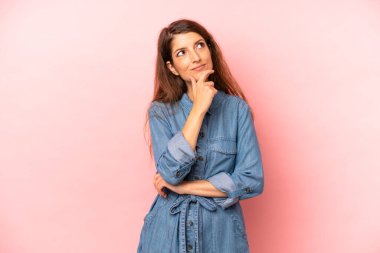 Genç ve güzel bir kadın düşünceli, meraklı ya da hayal kuruyor, hayal kuruyor ve mekanı kopyalamak için yukarı bakıyor.