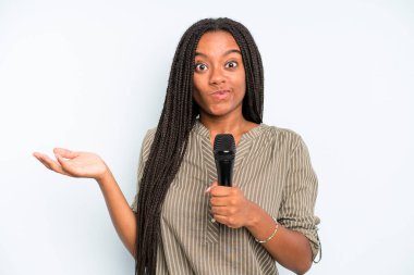 Siyah güzel kadın şaşkın, şaşkın ve şüpheci hissediyor. Mikrofonlu şarkıcı