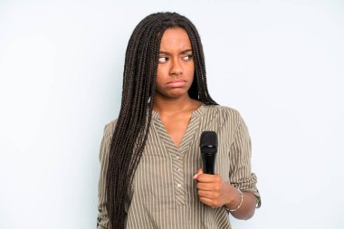 Siyah, güzel bir kadın üzgün, üzgün ya da kızgın hissedip yan tarafa bakıyor. Mikrofonlu şarkıcı