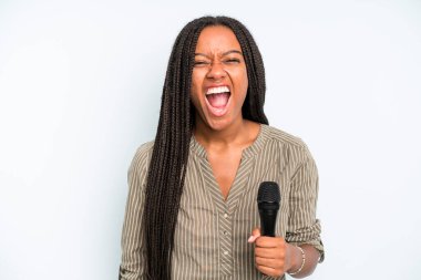 Siyah, güzel bir kadın agresif bir şekilde bağırıyor, çok kızgın görünüyor. Mikrofonlu şarkıcı