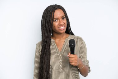 Siyah güzel kadın şaşkın ve şaşkın hissediyor. Mikrofonlu şarkıcı