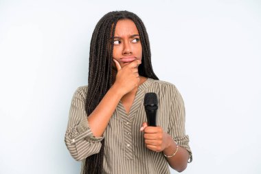 Siyahi güzel kadın düşünüyor, kuşkulu ve şaşkın hissediyor. Mikrofonlu şarkıcı