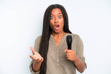 Siyah güzel bir kadın son derece şaşırmış ve şok olmuş hissediyor. Mikrofonlu şarkıcı