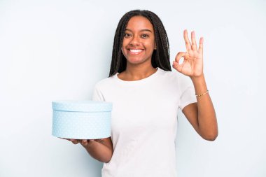 Siyah, güzel bir kadın kendini mutlu hissediyor, iyi bir jestle onaylıyor. hediye kutusu konsepti