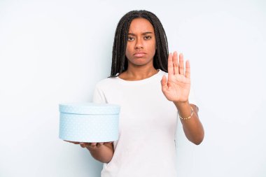 Siyahi güzel kadın ciddi görünüyor. Avuç içi gösteriyor. Durma hareketi yapıyor. hediye kutusu konsepti