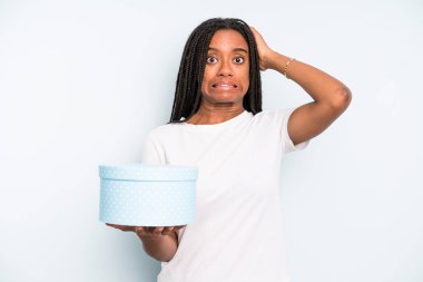 Siyah güzel bir kadın stresli, endişeli ya da korkmuş hissediyor, elleri başının üstünde. hediye kutusu konsepti