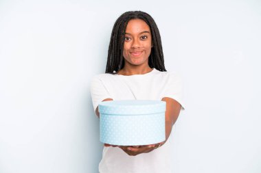 Siyahi, güzel bir kadın dostça gülümsüyor ve bir konsept sunuyor. hediye kutusu konsepti