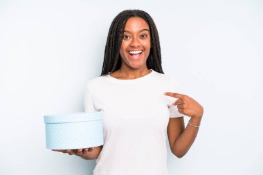 Siyah, güzel bir kadın kendini mutlu hissediyor ve heyecanlı bir şekilde kendini işaret ediyor. hediye kutusu konsepti