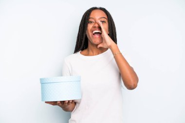 Zenci, güzel bir kadın kendini mutlu hissediyor. Elleri ağzının kenarında bağırıyor. hediye kutusu konsepti