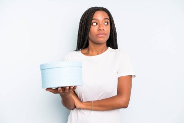 Siyah, güzel bir kadın omuz silkiyor, kafası karışık ve kararsız. hediye kutusu konsepti