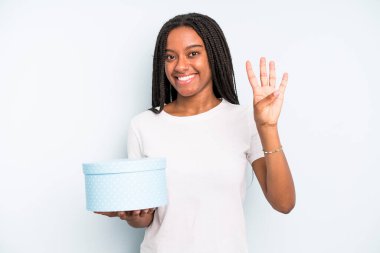 Siyah, güzel bir kadın gülümsüyor ve arkadaş canlısı görünüyor, dört numarayı gösteriyor. hediye kutusu konsepti