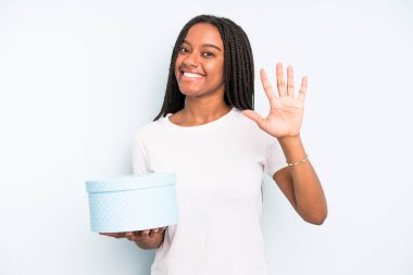 Siyah, güzel bir kadın gülümsüyor ve arkadaş canlısı görünüyor. Beş numarayı gösteriyor. hediye kutusu konsepti