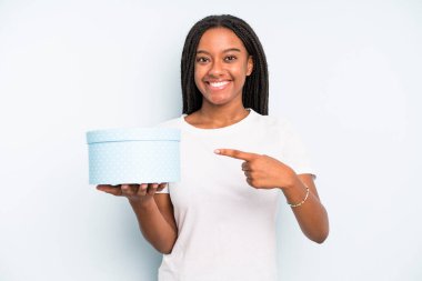 Siyah, güzel bir kadın neşeyle gülümsüyor, mutlu hissediyor ve bir tarafı işaret ediyor. hediye kutusu konsepti