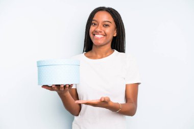 Siyah, güzel bir kadın, neşeli bir şekilde gülümsüyor, mutlu hissediyor ve bir konsept gösteriyor. hediye kutusu konsepti