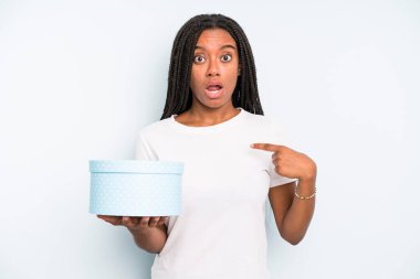 Zenci güzel bir kadın şok olmuş ve ağzı açık, kendini işaret ederek şaşırmış görünüyor. hediye kutusu konsepti