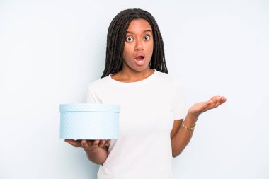 Zenci güzel kadın şaşırmış ve şok olmuş görünüyor. Çenesi düşmüş ve elinde bir nesne tutuyor. hediye kutusu konsepti