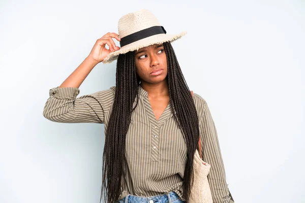 Siyah güzel kadın mutlu bir şekilde gülümsüyor ve hayal kuruyor ya da şüphe ediyor. yaz konsepti