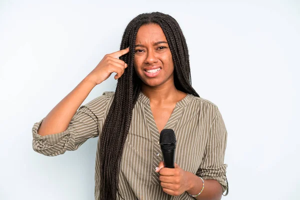 Siyah, güzel bir kadın kafası karışık ve şaşkın hissediyor, deli olduğunu gösteriyor. Mikrofonlu şarkıcı