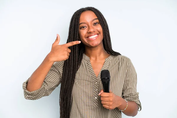 Siyahi, güzel bir kadın, kendine güvenerek gülümsüyor. Mikrofonlu şarkıcı