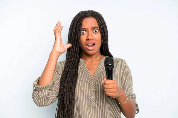 Siyah, güzel bir kadın ellerini havaya kaldırarak çığlık atıyor. Mikrofonlu şarkıcı