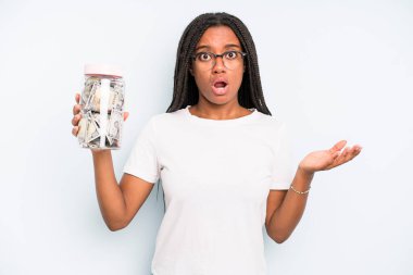 black pretty woman looking surprised and shocked, with jaw dropped holding an object. savings concept