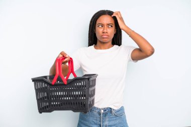 black pretty woman feeling puzzled and confused, scratching head. empty shopping basket