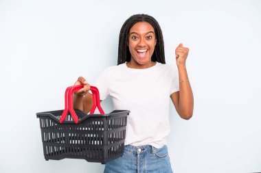 black pretty woman feeling shocked,laughing and celebrating success. empty shopping basket