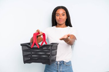 black pretty woman smiling happily with friendly and  offering and showing a concept. empty shopping basket