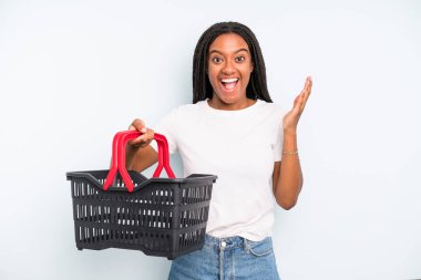 black pretty woman feeling happy and astonished at something unbelievable. empty shopping basket